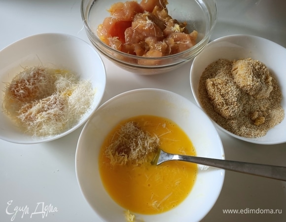 Обмакнуть каждый кусочек куриного филе в яйце, обвалять в пармезане, затем опять в яйце и в панировочных сухарях. Запанированные кусочки выложить на доску, смахнуть лишние сухари.