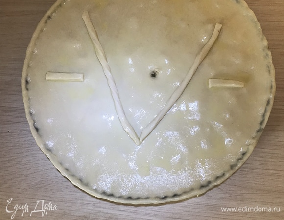 Раскатываем слоеное тесто, накрываем форму с начинкой, защипываем края. Взбиваем молоко и желток от яйца и смазываем тесто. Из остатков теста можно вырезать фигурки, выложить сверху и тоже смазать. Ставим в разогретую до 220°C духовку на 30–40 минут.