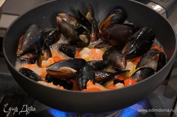 Приготовить соус: в сковороде вок разогреть по 1 ст. ложке оливкового и сливочного масла, выложить измельченный чеснок чили, имбирь, помидоры и мидии, влить вино, накрыть крышкой и прогреть, добавить креветки и готовить под крышкой еще несколько минут, затем добавить кальмаров с осьминогами, все перемешать, переложить соус в кастрюлю с супом и довести кипения.