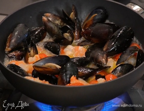 Приготовить соус: в сковороде вок разогреть по 1 ст. ложке оливкового и сливочного масла, выложить измельченный чеснок чили, имбирь, помидоры и мидии, влить вино, накрыть крышкой и прогреть, добавить креветки и готовить под крышкой еще несколько минут, затем добавить кальмаров с осьминогами, все перемешать, переложить соус в кастрюлю с супом и довести кипения.