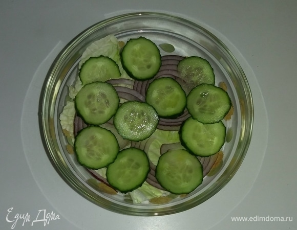 Затем на квадратики листьев китайского салата нужно положить слой нарезанного лука и затем — слой нарезанных огурцов.