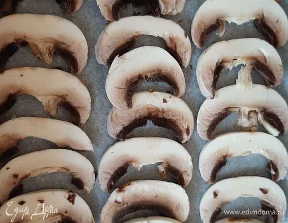 Шампиньоны моем, очищаем и режем на пластинки, укладываем первым слоем в форму, которую выстилаем бумагой для запекания. Это для того, чтобы сыр остался в пироге. Можно использовать консервированные грибы.