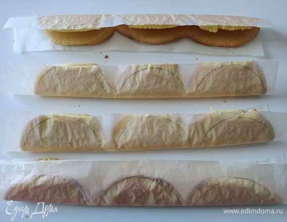 Достать противень, разрезать пергаментную бумагу на полоски и осторожно сложить пополам. Делать это надо быстро, пока бисквит не остыл. Остудить.