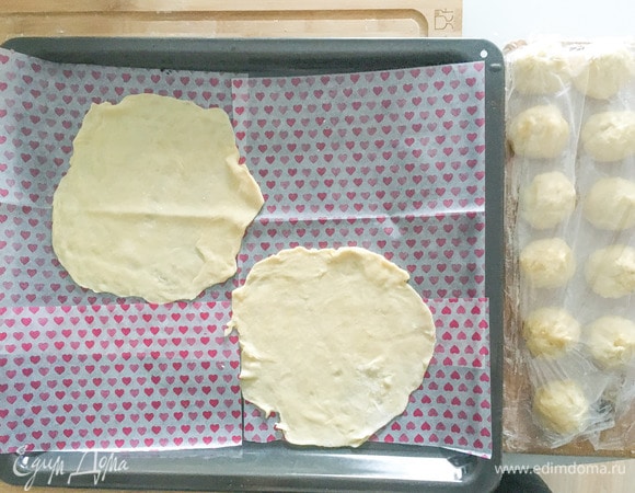 Достать тесто, раскатать каждый шарик максимально тонко, выложить на бумагу для выпечки. Выпекать при 200°C 4–5 минут до золотистого цвета.