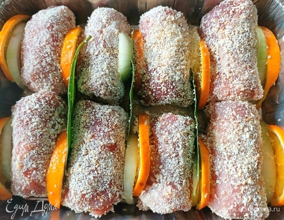 Рулетики выложить в форму для запекания. Между ними уложить по паре лавровых листиков, лук и дольки апельсина. Полить оливковым маслом.