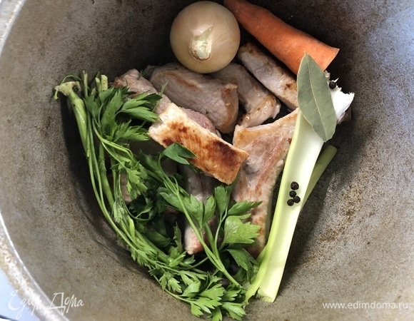 Мясо желательно брать на кости, нарезаем на средние куски, обжариваем в сковороде с растительным маслом до золотистой корочки. Выкладываем в емкость, где будем варить, добавляем веточки петрушки, морковь, мытую луковицу, сельдерей, лавровый лист, перец горошком. Заливаем 2,5 литрами воды, доводим до кипения, уменьшаем огонь и томим, пока мясо не начнет отходить от кости (1,5–2 часа).
