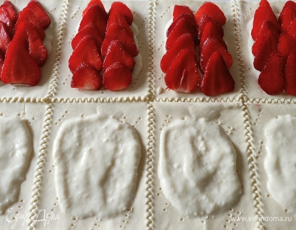 Тесто переложить на противень. Наколоть вилкой. На каждый прямоугольник выложить 2–3 ложки крема, затем — нарезанную клубнику.