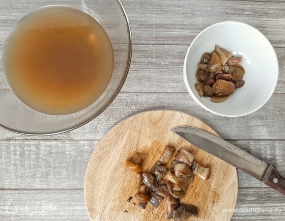 Сливаем через сито грибной бульон. Убираем специи, лук и чеснок. Крупные части грибов разрезаем, но не мелко. Бульон можно перелить обратно в кастрюлю и поставить на медленный огонь, чтобы бульон был горячим.