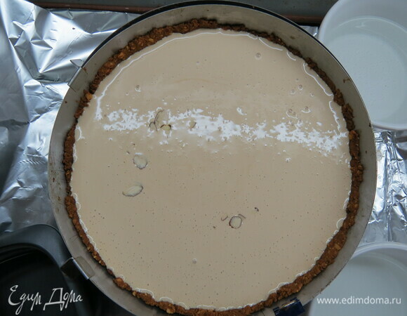 Через час достать чизкейк, вылить на него сметанную заливку, посыпать лепестками и выпекать еще около 30 минут. Дать чизкейку полностью остыть в духовке, далее убрать в холодильник на ночь.