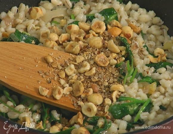 Шпинат отправить к луку с чесноком и дать ему поплыть, затем добавить сливочное масло и готовую перловку, все перемешать, выложить в сковороду орехи со специями и топинамбур.