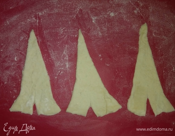 Затем каждый прямоугольник теста разрезать на треугольники и внизу каждого сделать разрез длиной около 1 см. Из каждой половины теста получается около 6–7 треугольников.