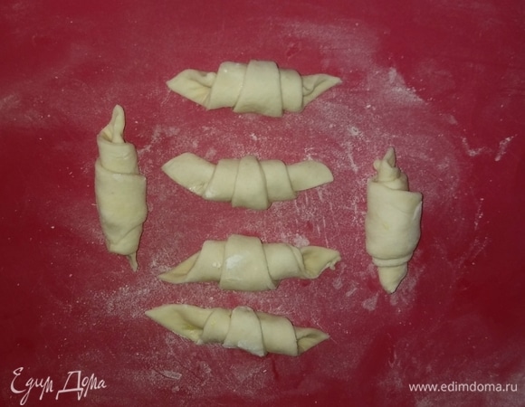 Скатать треугольники теста с начинкой в такие вот заготовки. Смазать их белком и чуть-чуть посыпать сахарным песком.