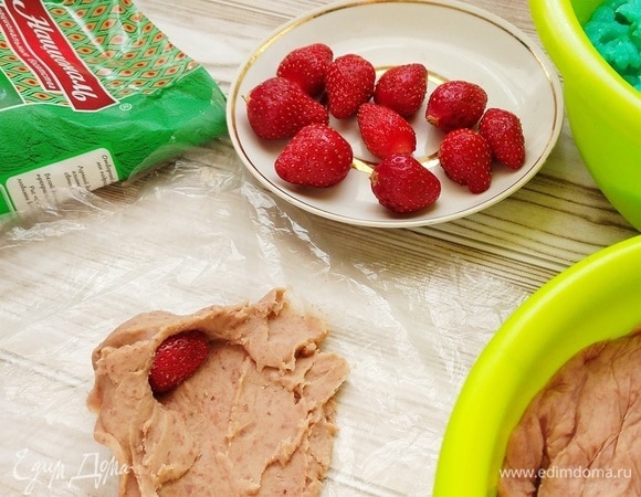 Из фасолевой пасты делаем лепешку. Удобнее раскатывать тесто в пищевой пленке. В серединку кладем клубничку и формируем шарик.