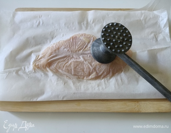 Куриное филе положить между листами пергаментной бумаги и отбить.