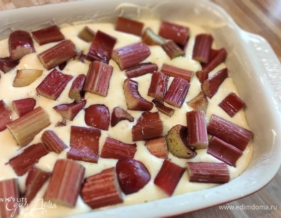 Выложить остальную часть ревеня. Выпекать в духовке, предварительно разогретой до 150°C, в течение примерно 35 минут и подавать, посыпав сахарной пудрой.