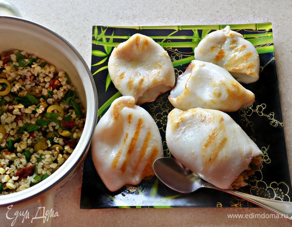 Добавьте нарезанную петрушку, томаты и оливки к булгуру, поперчите и, при необходимости, слегка подсолите. Хорошо перемешайте начинку. С помощью маленькой ложки аккуратно нафаршируйте кальмары, немного утрамбовывая в них начинку.