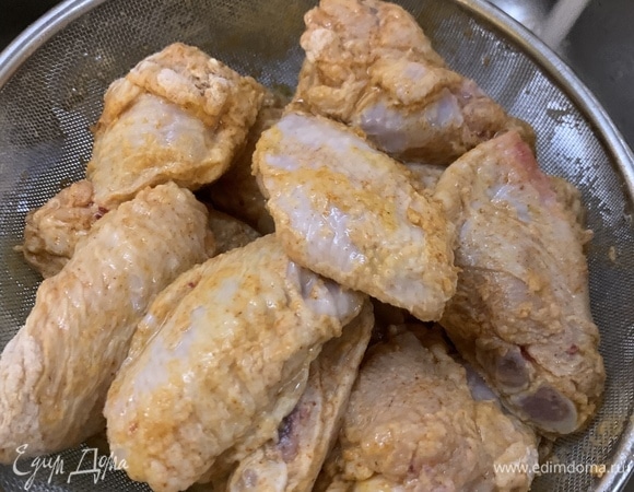 Кладем крылья в дуршлаг, стряхиваем лишнюю муку и обливаем их водой.