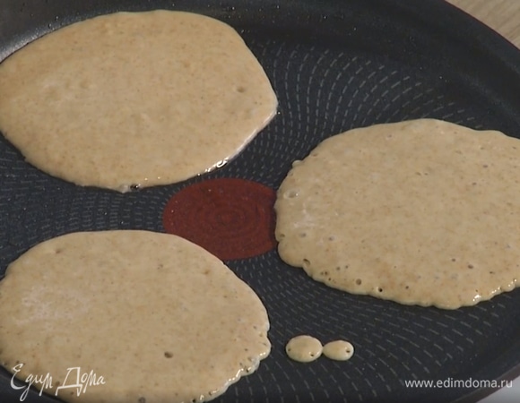 Разогреть блинную сковороду, кисточкой смазать ее растительным маслом и, наливая половником тесто, жарить блинчики по 2 минуты с каждой стороны.