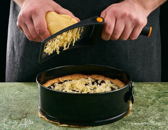 Чернику аккуратно промойте и обсушите. Поставьте форму с тестом в духовку и выпекайте 15 минут при 180 ℃. Вытащите тесто из духовки и выложите ягоды. Замороженный кусок теста натрите поверх черники. Запекайте еще 25 минут.