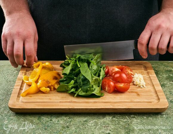 С печеного перца снимите кожуру, почистите и нарежьте небольшими кусочками. Шпинат промойте и обсушите. Черри промойте и нарежьте на половинки. Чеснок мелко порубите.