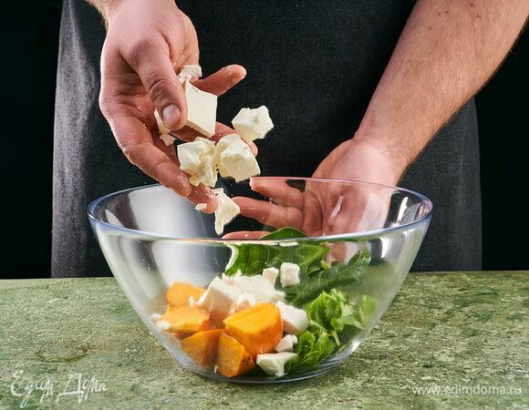 Выложите в салатник шпинат, кинзу, кусочки хурмы и козьего сыра.