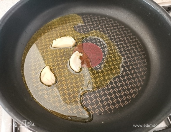 В разогретую сковороду налить оливковое масло. Чеснок очистить, раздавить тыльной стороной ножа и выложить в сковороду. Обжарить чеснок в течение 30 секунд с обеих сторон и убрать со сковороды.