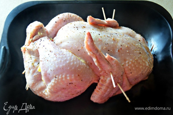Сколите отверстия с помощью шпажек или зубочисток, также можете зашить кулинарной нитью. Крылья прижмите к телу курицы с помощью шпажек. Кусочки сливочного масла распределите под крыльями и окорочками курицы, а также немного смажьте маслом поверхность курицы. Выпекайте курицу в нагретой до 200°C духовке 20 минут, а затем убавьте температуру до 180°C и готовьте 1–1,15 ч до готовности курицы. Не забывайте периодически поливать курицу образовавшимся в противне соком. Во время приготовления концы крылышек лучше завернуть в фольгу, чтобы не подгорали.