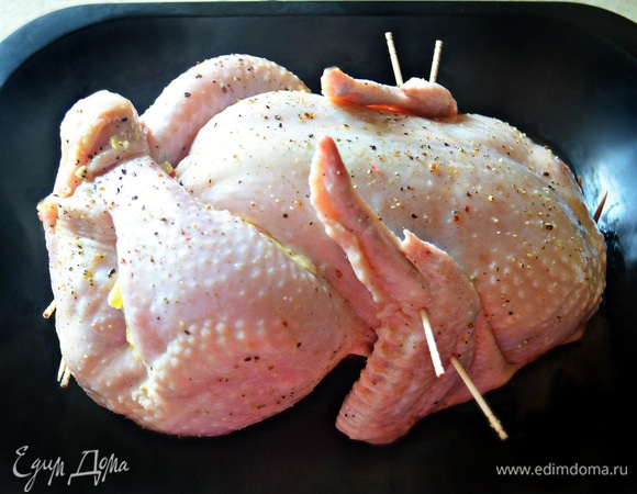 Сколите отверстия с помощью шпажек или зубочисток, также можете зашить кулинарной нитью. Крылья прижмите к телу курицы с помощью шпажек. Кусочки сливочного масла распределите под крыльями и окорочками курицы, а также немного смажьте маслом поверхность курицы. Выпекайте курицу в нагретой до 200°C духовке 20 минут, а затем убавьте температуру до 180°C и готовьте 1–1,15 ч до готовности курицы. Не забывайте периодически поливать курицу образовавшимся в противне соком. Во время приготовления концы крылышек лучше завернуть в фольгу, чтобы не подгорали.