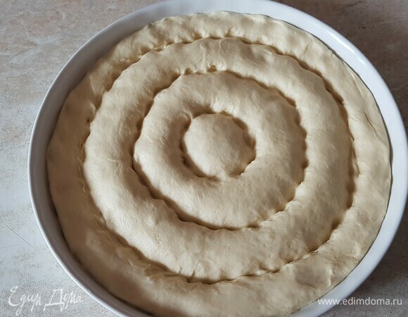Поднявшееся тесто распределить по всей форме. Сделать в нем круговые бороздки и оставить на 20 минут для подъема.