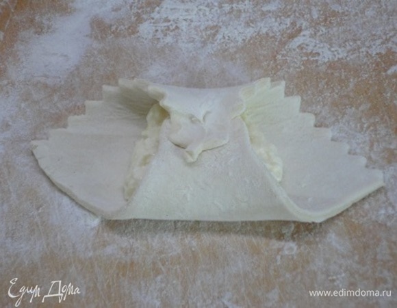 На каждый квадрат выложите начинку и соедините противоположные уголки, смазывая их белком и хорошо сжимая, чтобы при выпечке они не разошлись.