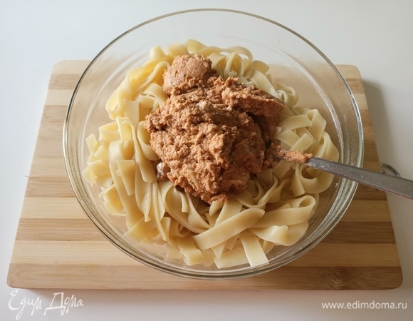 В песто добавить 1–2 ст. л. горячей воды, где варилась паста. Затем пасту выложить в глубокую миску, добавить песто и перемешать.