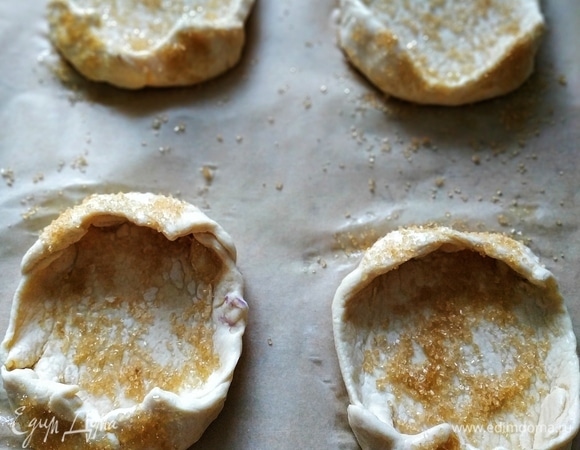 Квадрат слоеного дрожжевого теста разрежьте на 4 части. Сформируйте из теста бортики. Посыпьте бортики коричневым сахаром.