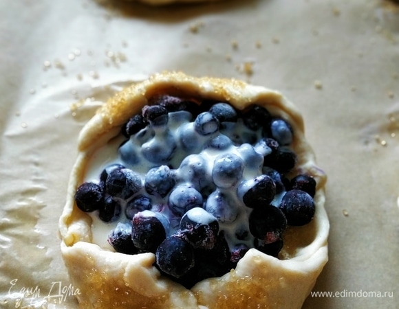 Наполните лодочки из теста черникой и залейте ягоды заливкой из сливочного сыра с яичным белком и сахаром (по желанию). Выпекайте при 180°C 15–18 минут до готовности.