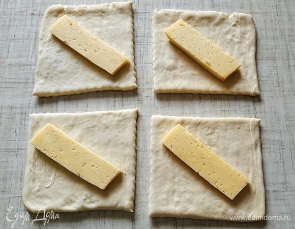 Слоеное дрожжевое тесто разрезать на 4 части. Положить кусочек сыра.