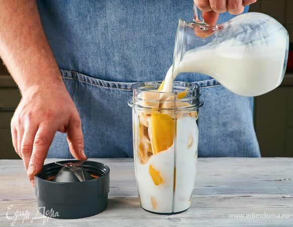 Выложите в стакан для смузи дольки банана и манго. Добавьте питьевой йогурт.