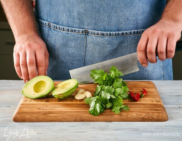 Займитесь соусом гуакамоле. Почистите авокадо и чеснок, помойте кинзу и перец чили.  
