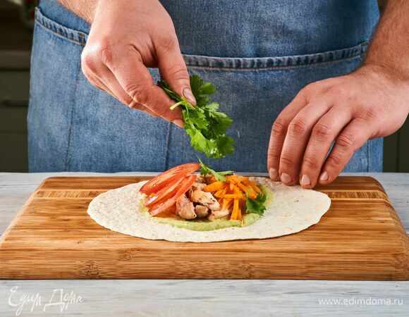 На прогретые лепешки выложите гуакамоле, куриную грудку, помидоры, морковь, кинза и сверните тартильи.