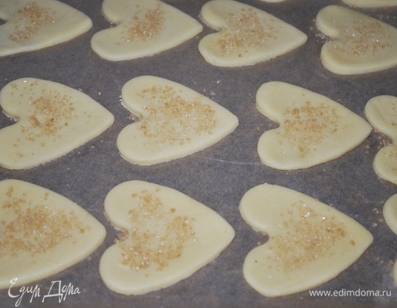 Вырежьте тесто формочками и выложите их на противень. Печенье посыпьте сверху коричневым сахаром. Выпекайте при 170°C примерно 10–12 минут, до готовности.