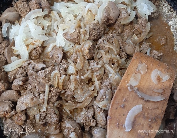 Когда печень поджарится, добавить к ней лук, сметану и воду. Хорошо перемешать и тушить 10 минут под крышкой на среднем огне.