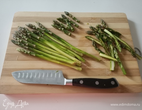 Спаржу очистить, срезать верхушки и разрезать их вдоль.