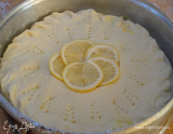 Раскатать вторую часть теста, круглой формой вырезать в центре отверстие диаметром примерно 8–10 см. Накрыть им начинку и защипнуть края. Выложить 5 тонких кружочков лимона в отверстие в центре. Кружочек теста, который вы вырезали, нарезать на сегменты и уложить поверх пирога (не пропадать же тесту).