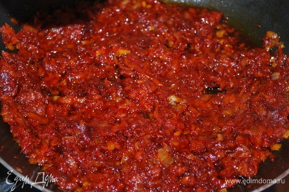 Добавьте томатную пасту, щепотку сахара и обжарьте все вместе примерно 4–5 минут.