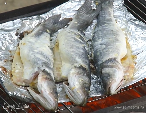 Рыбу снаружи и изнутри смазать специями и йогуртом, выложить на двойной слой пищевой фольги, поместить на гриль и пожарить.