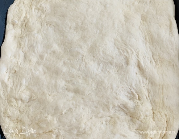 Берем большую форму для выпечки фокаччи со слегка высокими бортами, смазываем всю оливковым маслом. Перекладываем в нее тесто и разравниваем по всей форме.