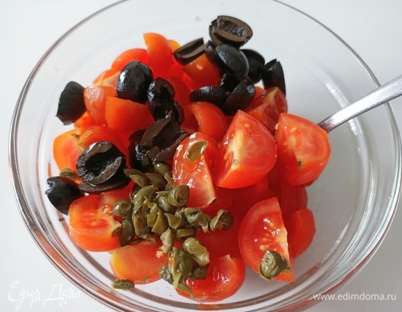 Помидоры разрезать на четыре части, добавить оливки, каперсы и ложку оливкового масла, перемешать.