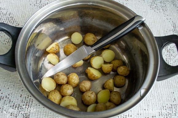 Маленькие картофелины разрезаем пополам. Молодую картошку чистить не нужно, достаточно вымыть щеткой или мочалкой. Чем мельче картошка, тем быстрее она сварится, в жару это актуально!