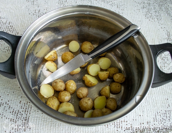 Маленькие картофелины разрезаем пополам. Молодую картошку чистить не нужно, достаточно вымыть щеткой или мочалкой. Чем мельче картошка, тем быстрее она сварится, в жару это актуально!