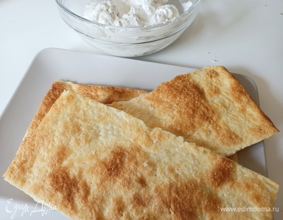 С готовых слоеных коржей срезать все неровности, подогнать под один размер и смазать кремом.