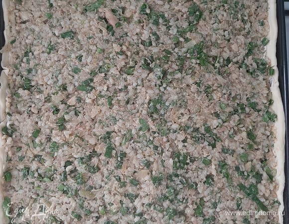 Слоеное дрожжевое тесто поделить на 2 неравные части (примерно 2/3 и 1/3), большую часть раскатать и выложить на противень, сформировать бортики. Выложить начинку.