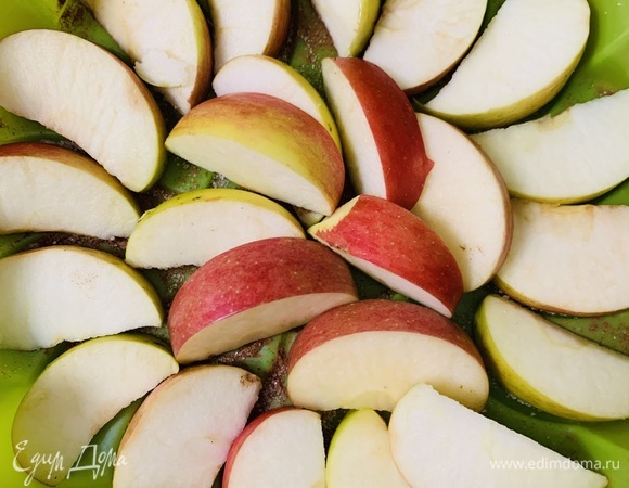Выкладываем на сахар половину из нарезанных на дольки яблок.